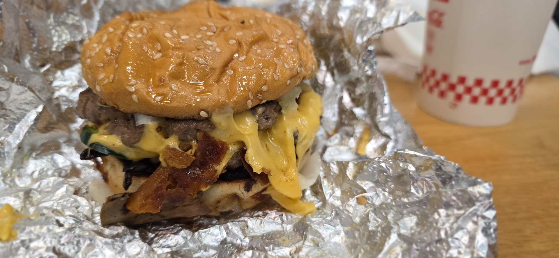 Un cheeseburger avec papier d'alu et boisson chez Five Guys à Lausanne.